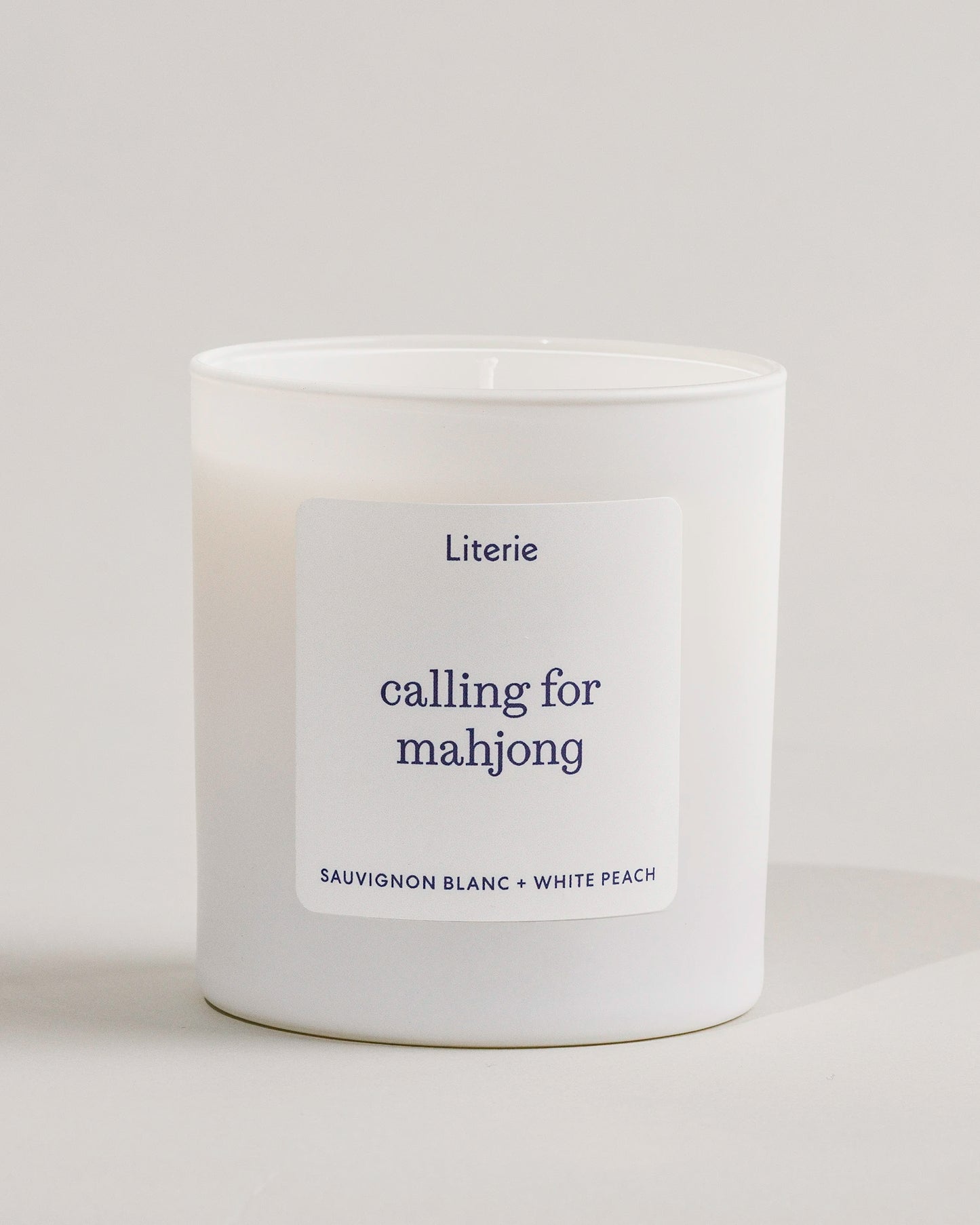 White 'calling for mahjong' candle with a label on a light gray background.