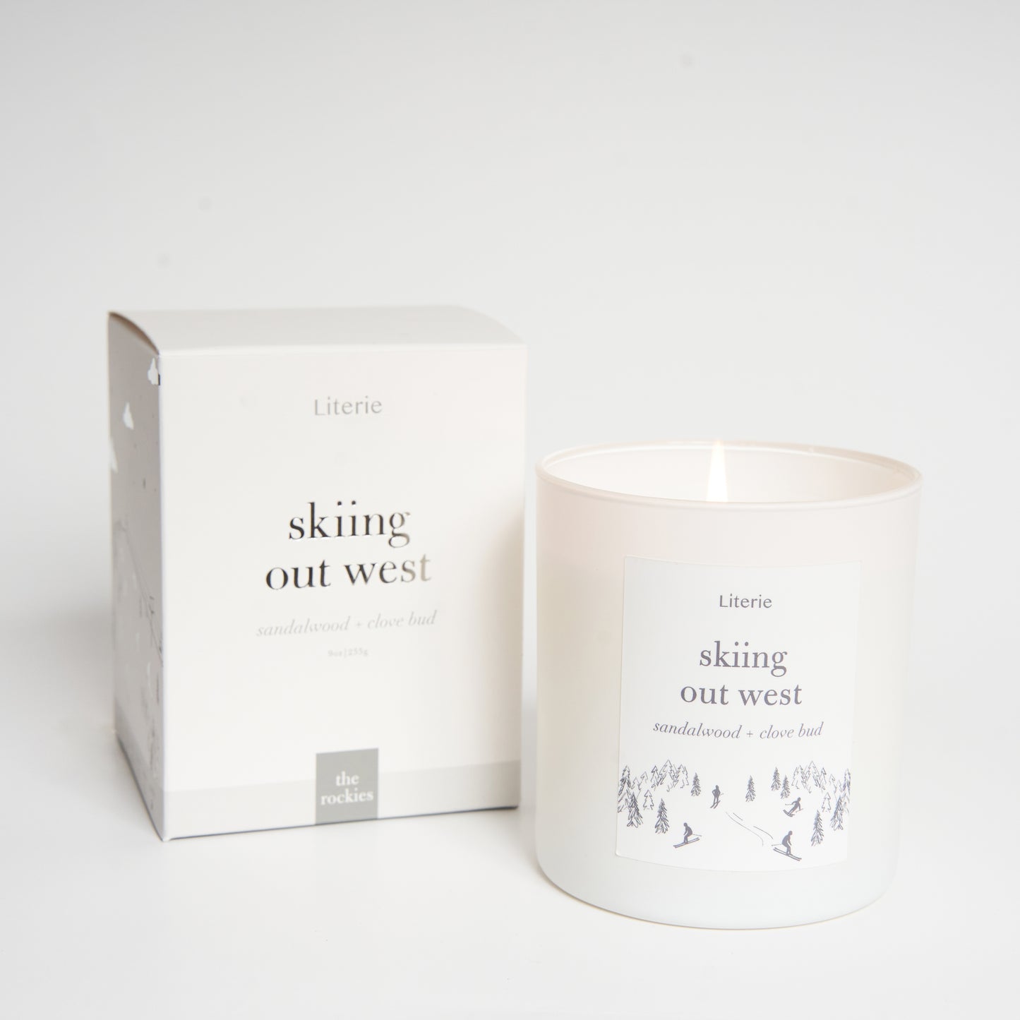 A candle with a label that reads 'skiing out west' alongside a matching box.