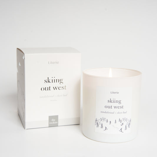 A candle with a label that reads 'skiing out west' alongside a matching box.