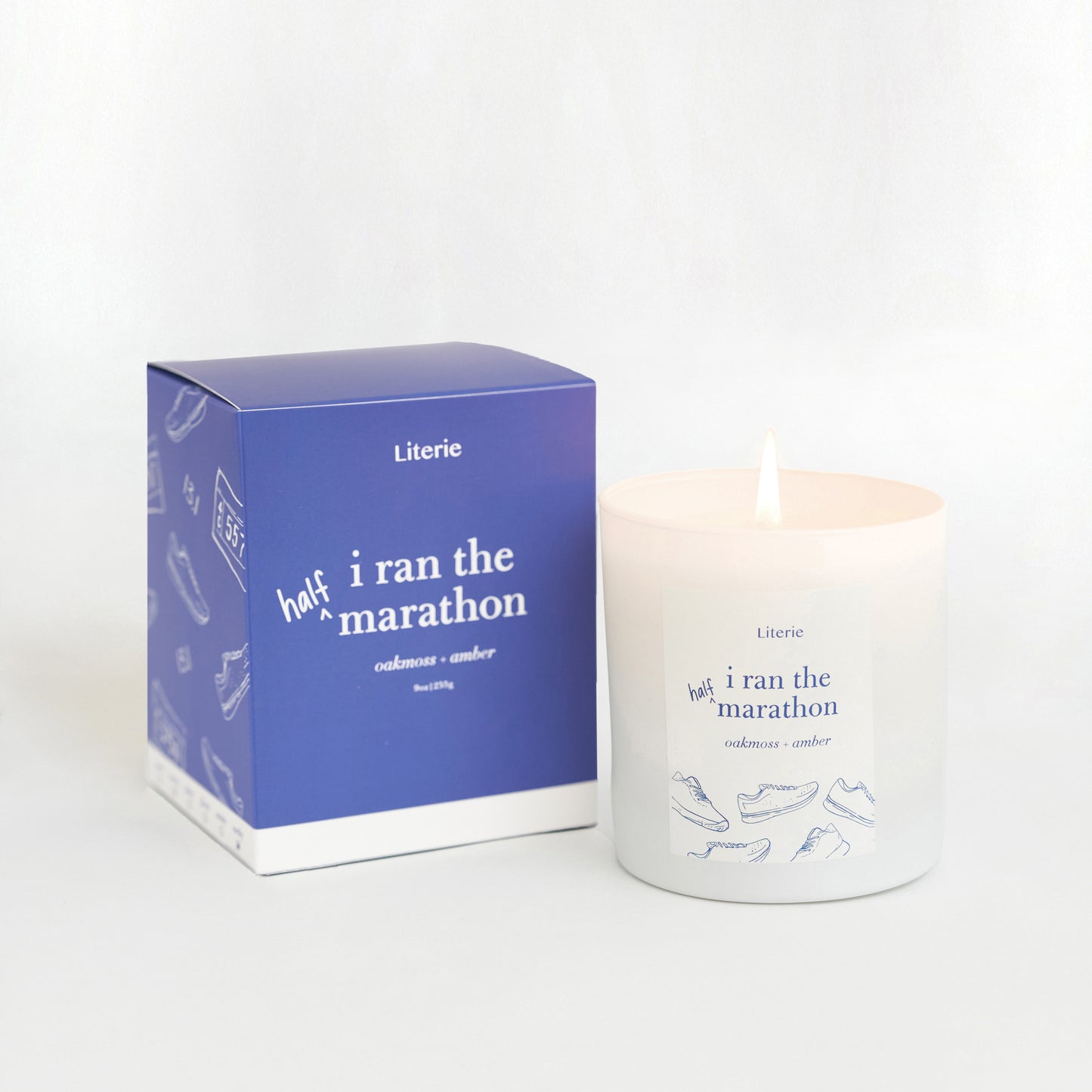 A candle with a label that reads 'half i ran the marathon' next to its packaging box which has a similar design.