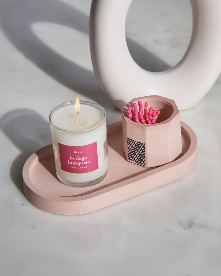 Pink pill shaped concrete candle tray with a pink candle and match holder.