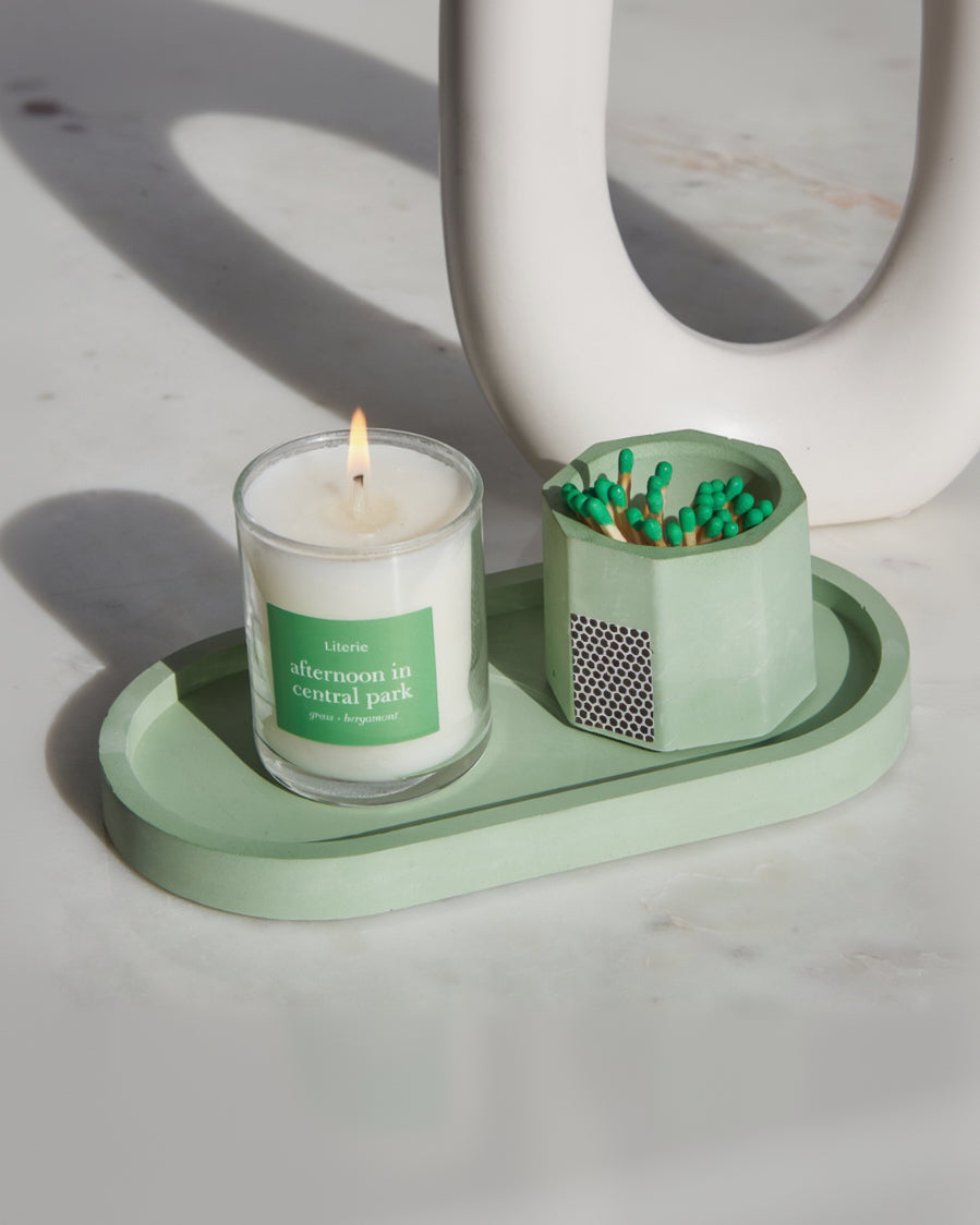 Matcha green pill shaped candle tray with green candle and green matchsticks.