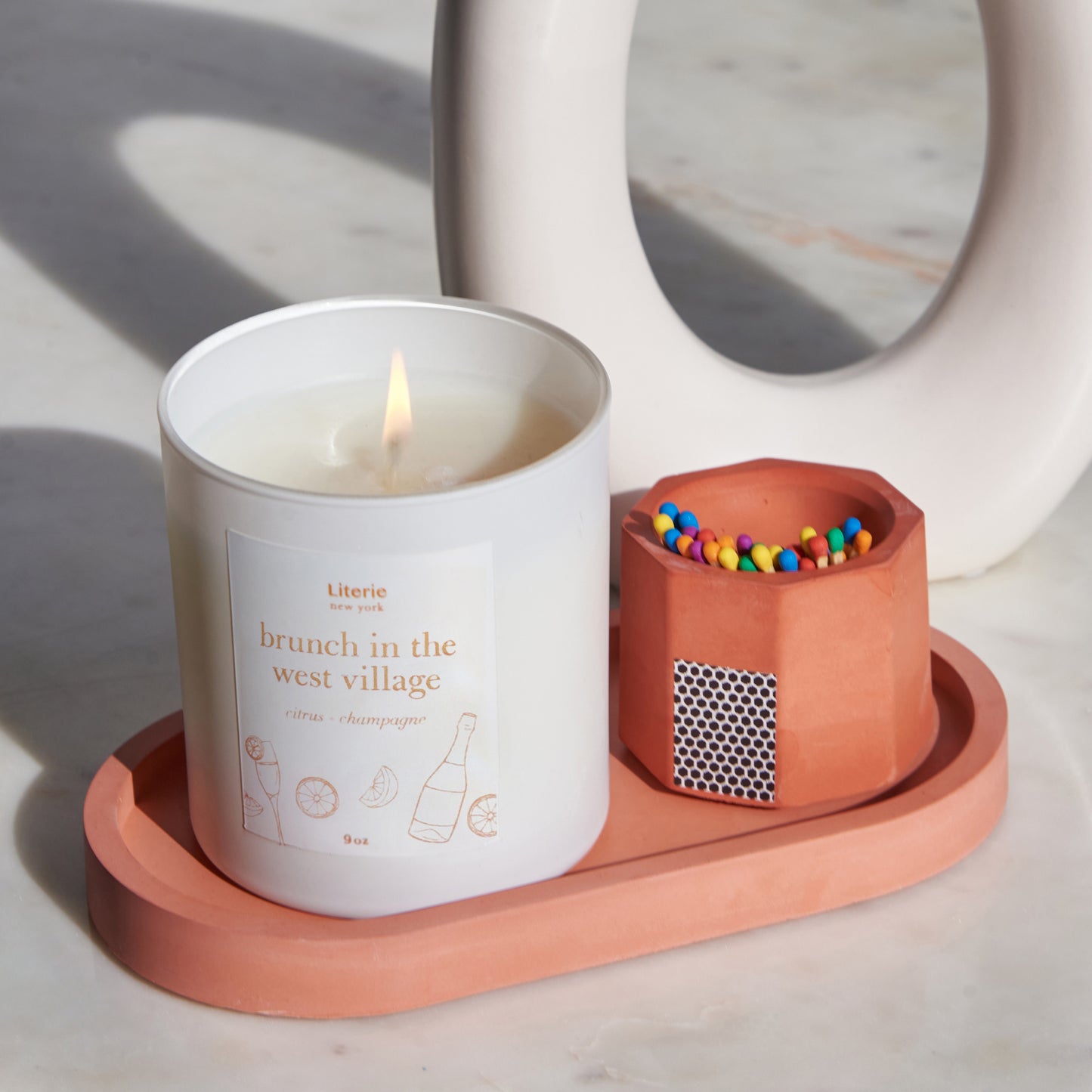 A orange concrete match holder with a hexagonal design with a candle on an orange tray.