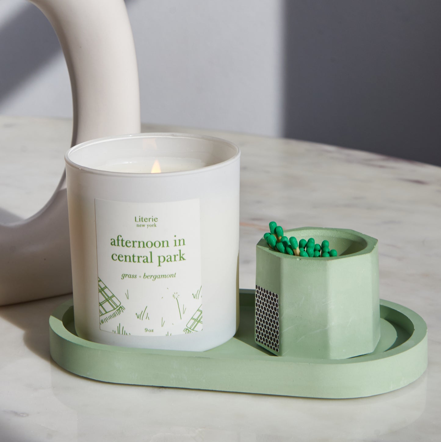 Matcha green pill shaped candle tray with candle and matches.