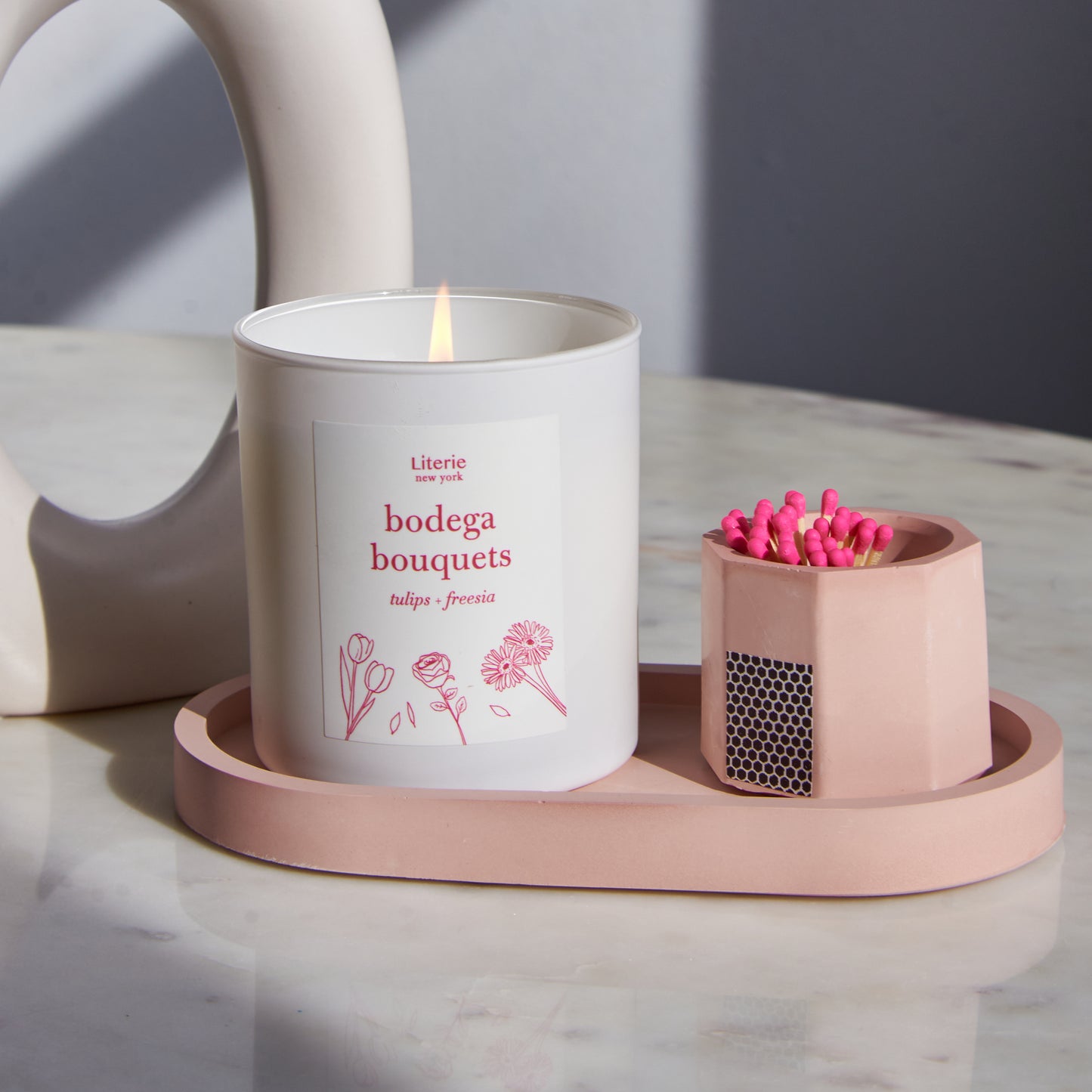A pink concrete match holder on a tray with a candle.