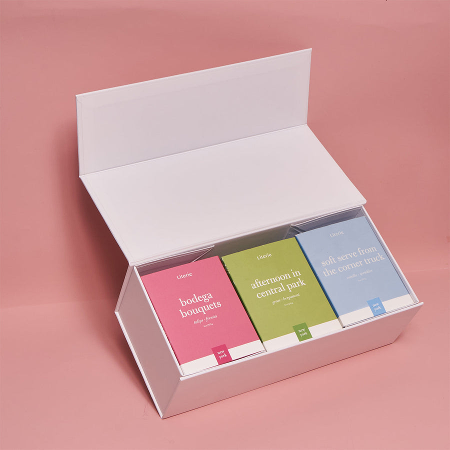 A custom gift box open to display three candles in different colors.