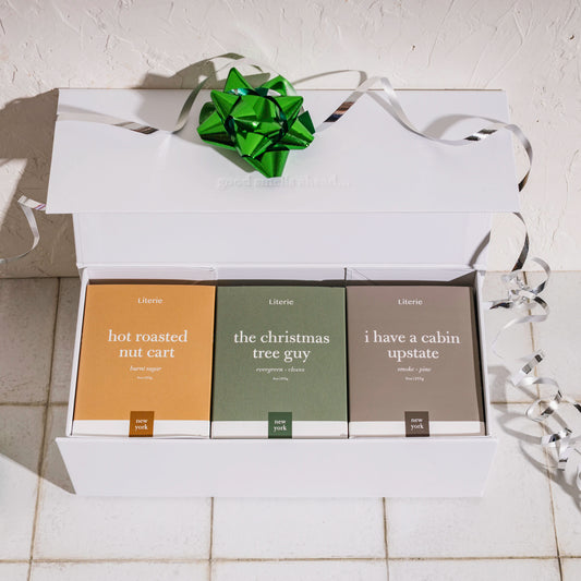 Set of candles in a gift box with ribbons on a light background.