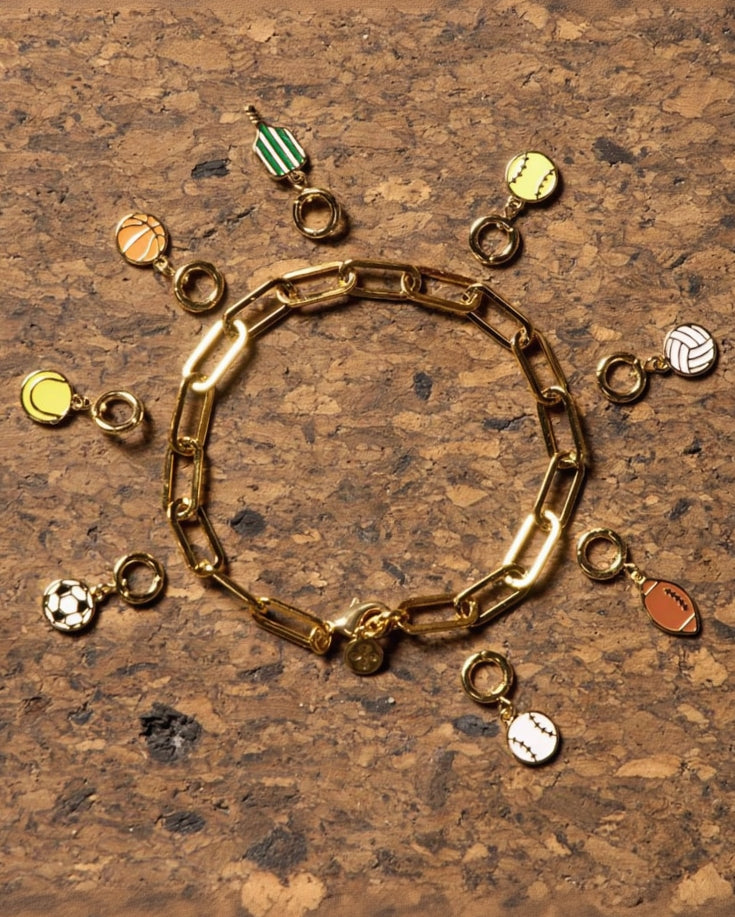 Various sports jewelry charms on cork background.