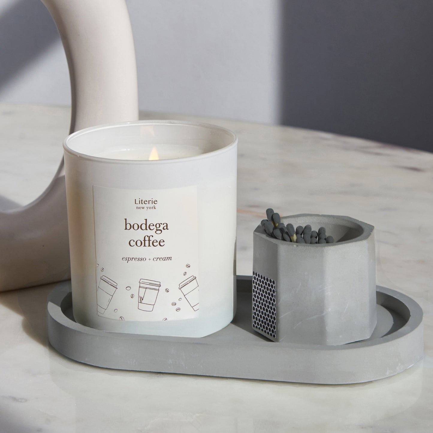Grey concrete match stick holder with matches on a matching tray with a candle.