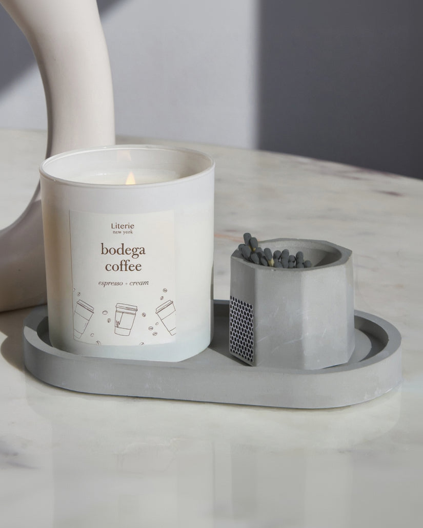 Grey concrete match stick holder with matches on a matching tray with a candle.