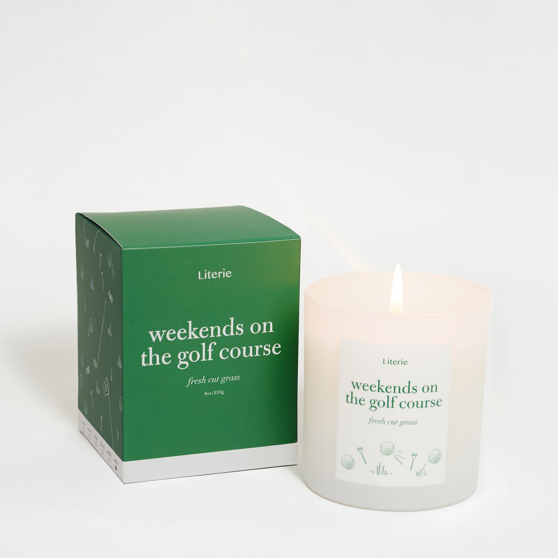 A candle with a label reading 'weekends on the golf course' alongside its green packaging box.