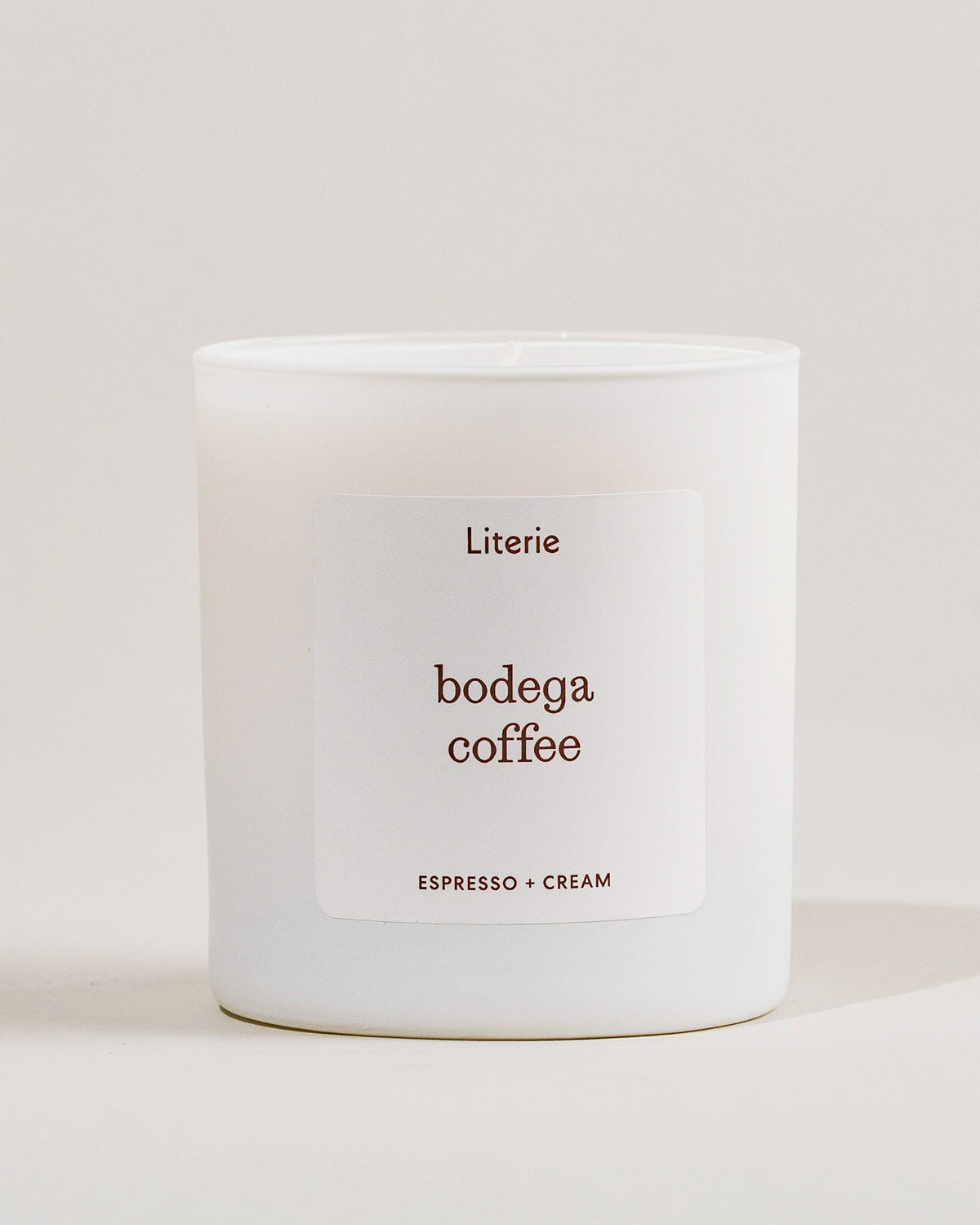White candle with 'bodega coffee' label from Literie on a light gray background