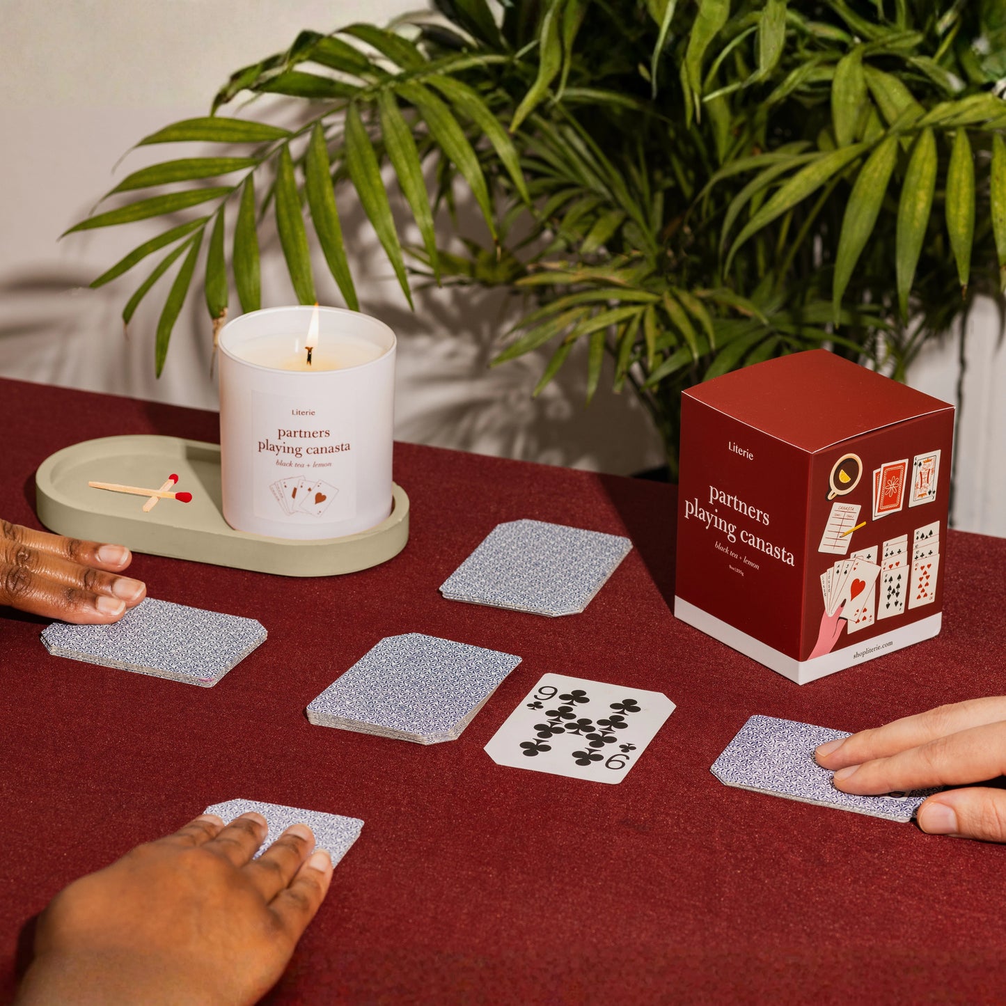 People playing canasta on a table with a candle and candle box.