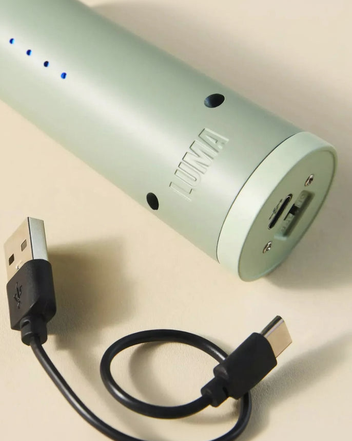 Light green lighter device with USB cable on a beige background.