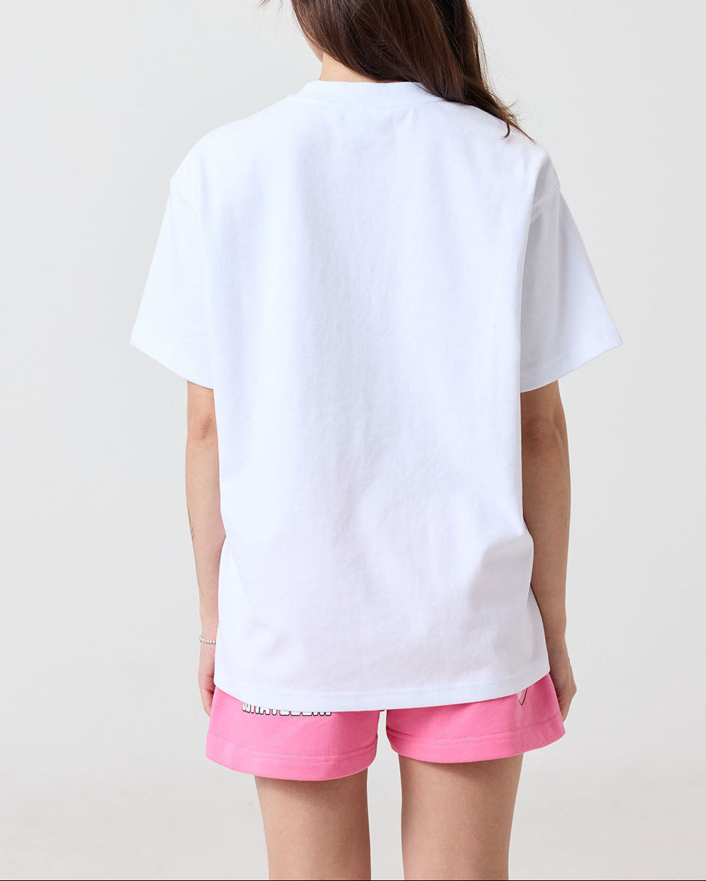 Person wearing a white t-shirt and pink shorts on a plain background
