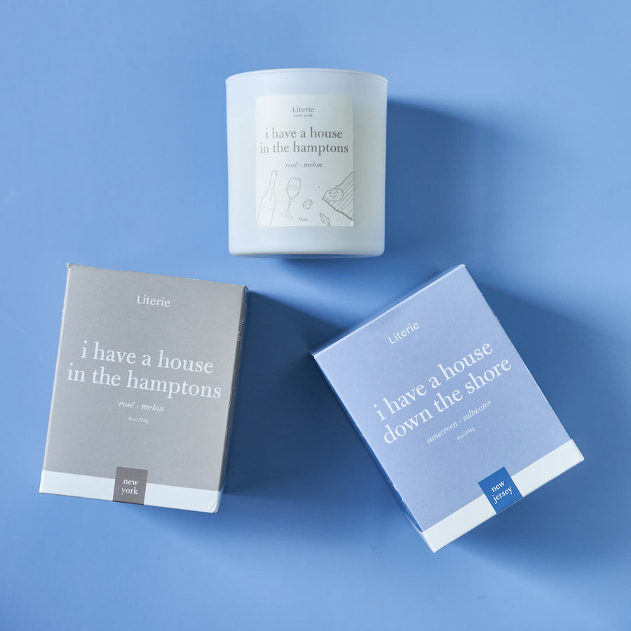 Two custom candles with packaging, one labeled 'I have a house in the hampshires' and the other 'down the shore'.