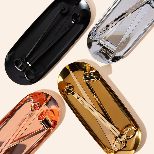 Four metallic candle care kits in black, silver, rose gold, and gold on a beige background.