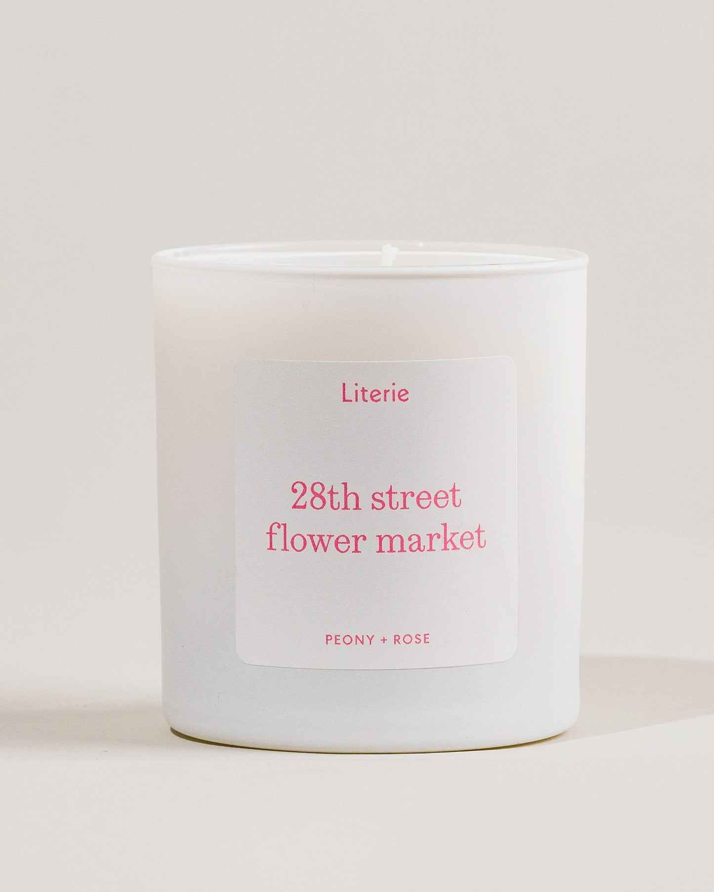 White candle with a '28th street flower market' label on a light gray background