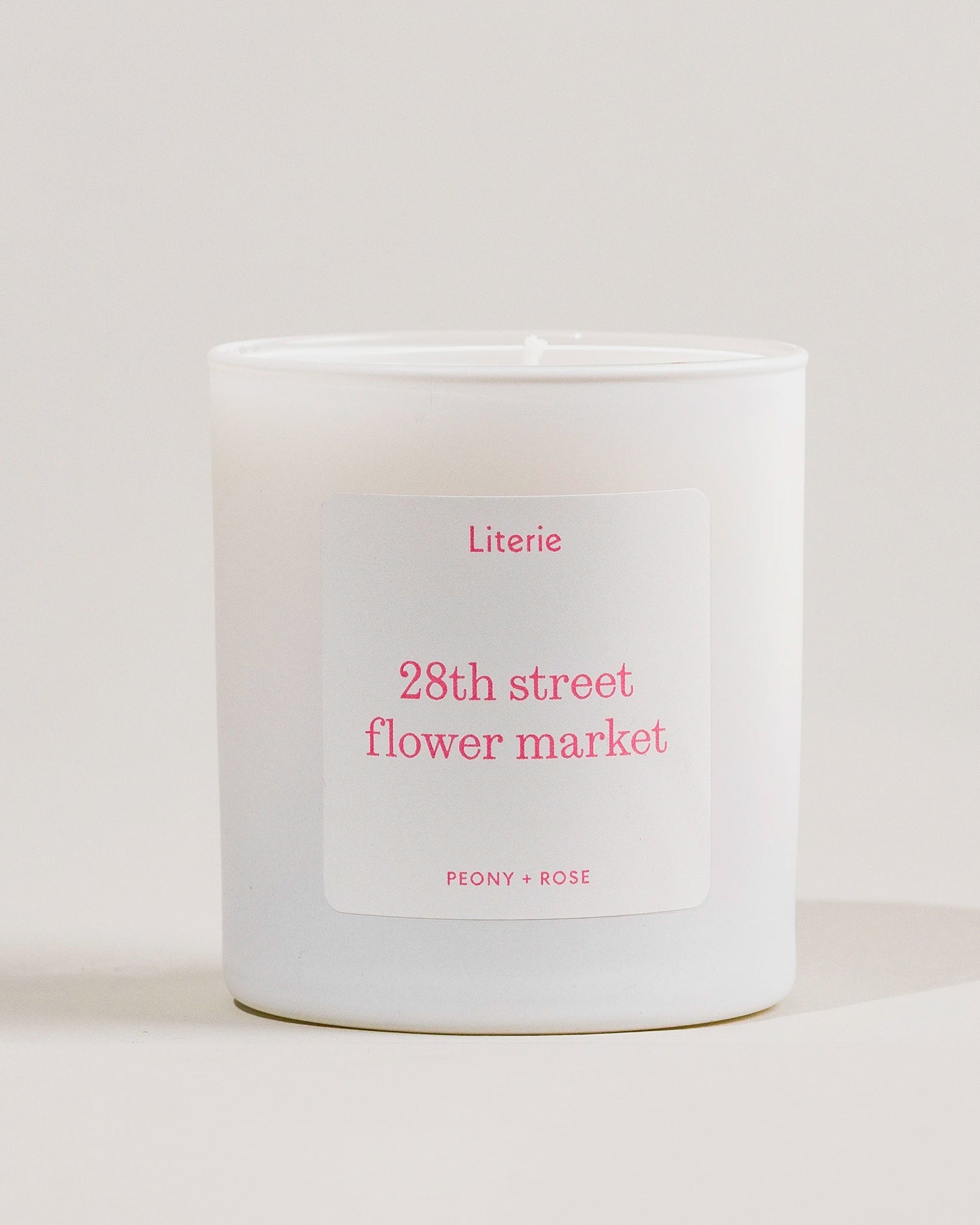 White candle with a '28th street flower market' label on a light gray background