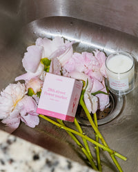 28th Street Flower Market (Little) candle by Literie in a sink with packaging and peonies. 
