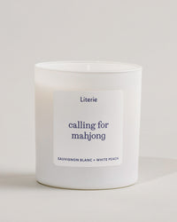 White 'calling for mahjong' candle with a label on a light gray background.