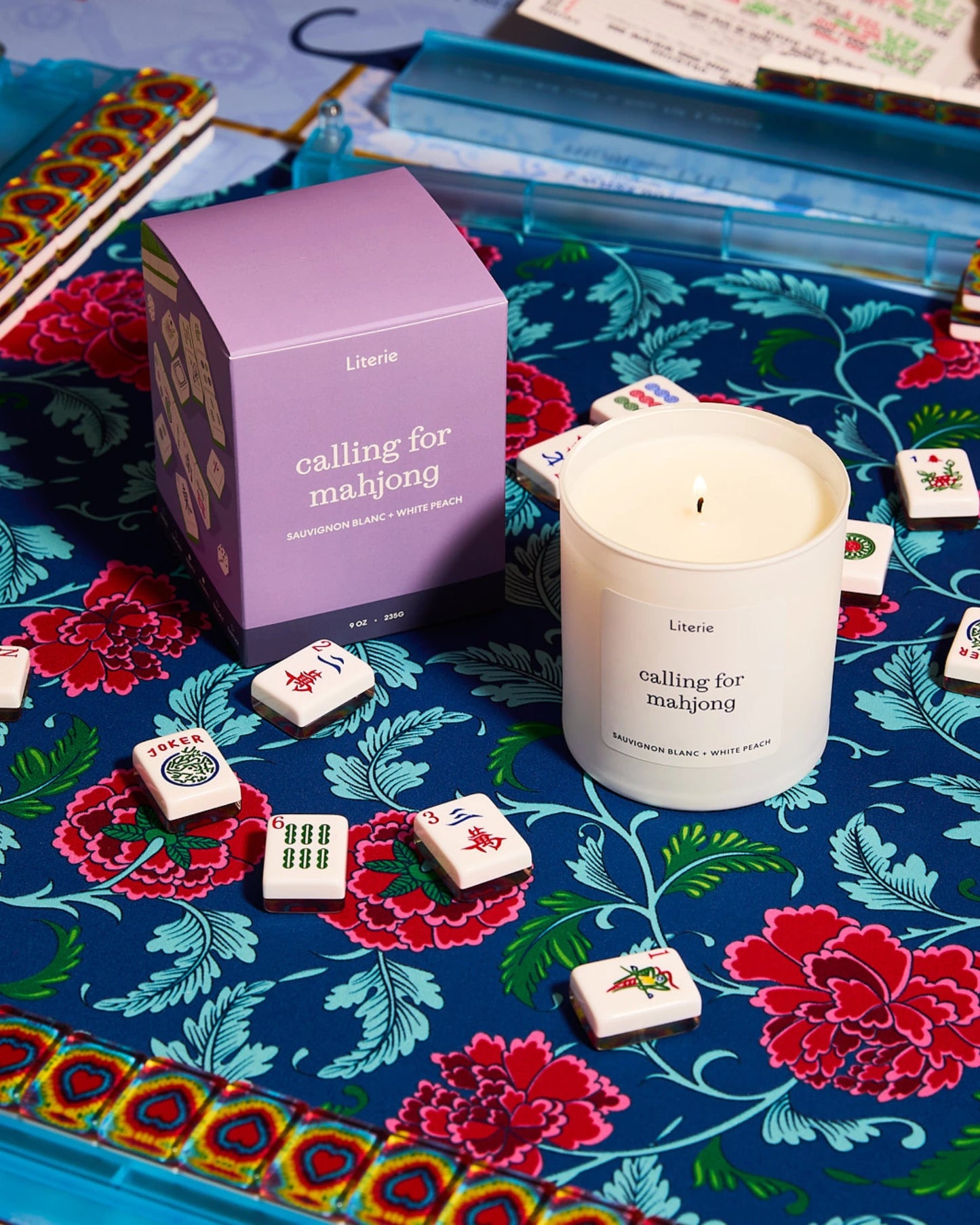 Mahjong mat with floral design, playing mahjong, and a Literie candle in the center.