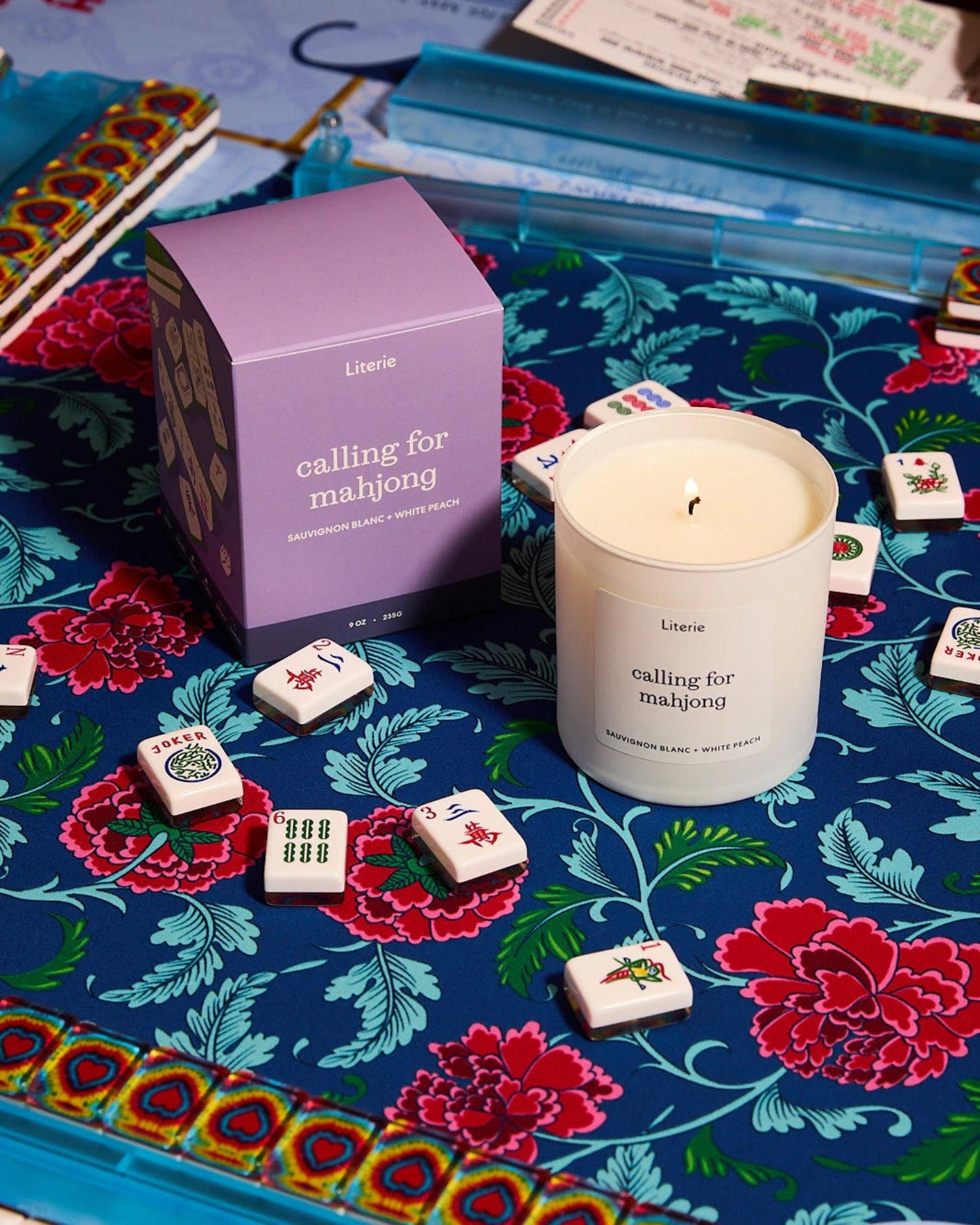 Mahjong mat with floral design, playing mahjong, and a Literie candle in the center.