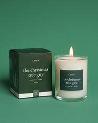 the christmas tree guy little candle with box on green background.