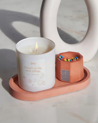 Brick colored pill shaped candle tray with candle and match holder.