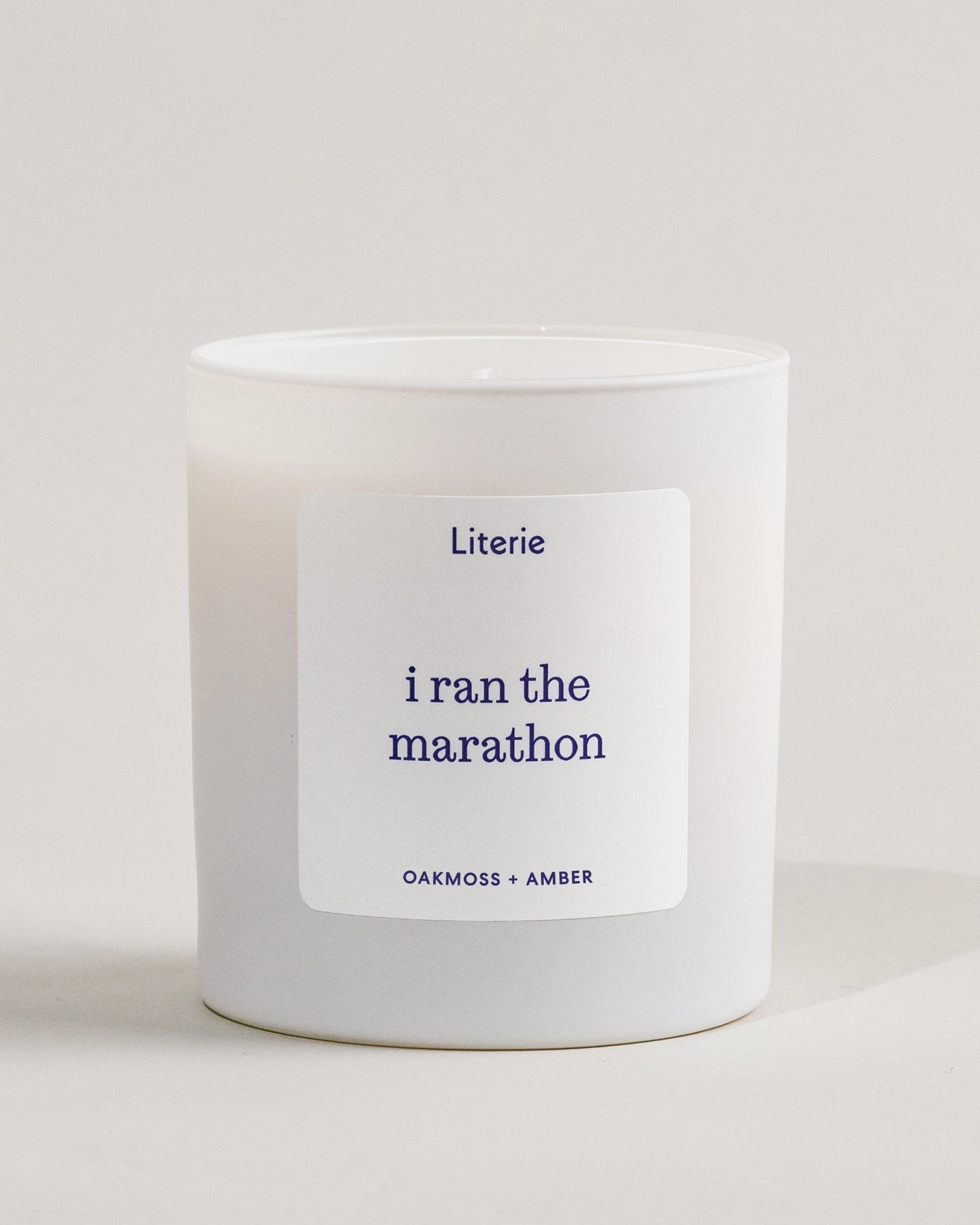 White candle with a label saying 'i ran the marathon' on a light gray background