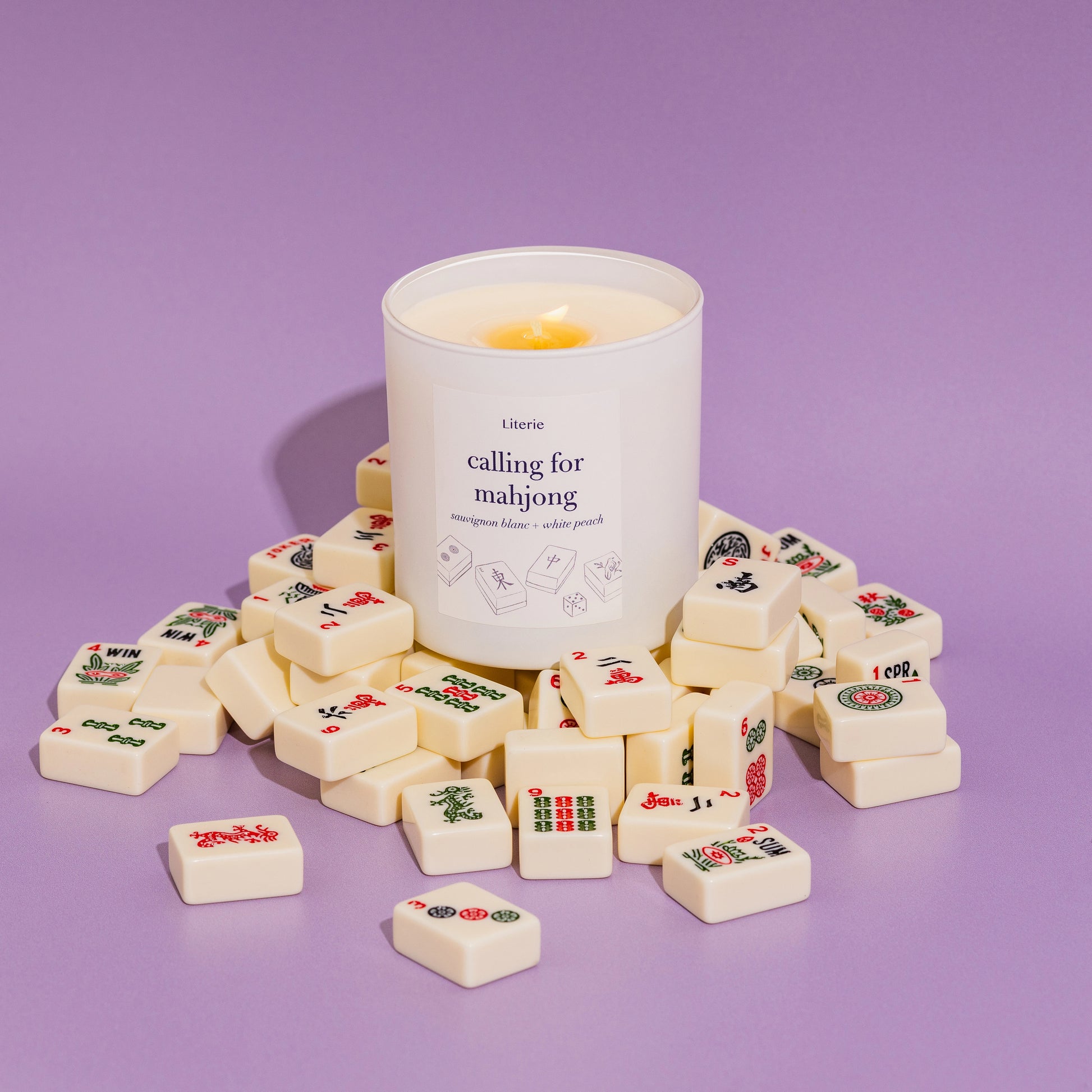 Candle labeled 'calling for mahjong' surrounded by mahjong tiles on a purple background.