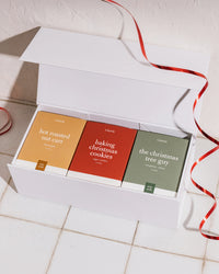 Gift box with 3 Literie candles and ribbon on a tile background.