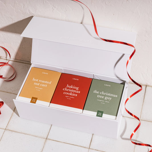 Gift box with 3 Literie candles and ribbon on a tile background.