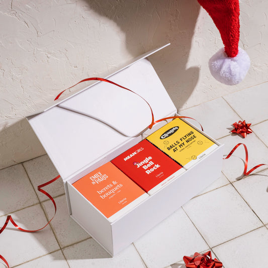 White gift box with Clueless, Mean Girls, and Emily In Paris candles with ribbon.
