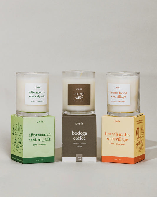 "Afternoon in Central Park", "Bodega Coffee" and "Brunch in the West Village" little candles and packaging by Literie on a grey background.