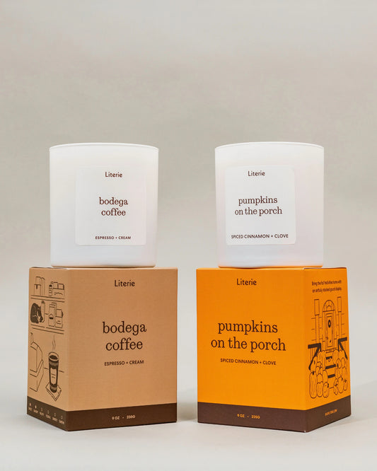 Two white Literie scented candles displayed on top of their respective boxes. The left candle is labeled 'bodega coffee' and the right candle is labeled 'pumpkins on the porch' to make the PSL candle duo.