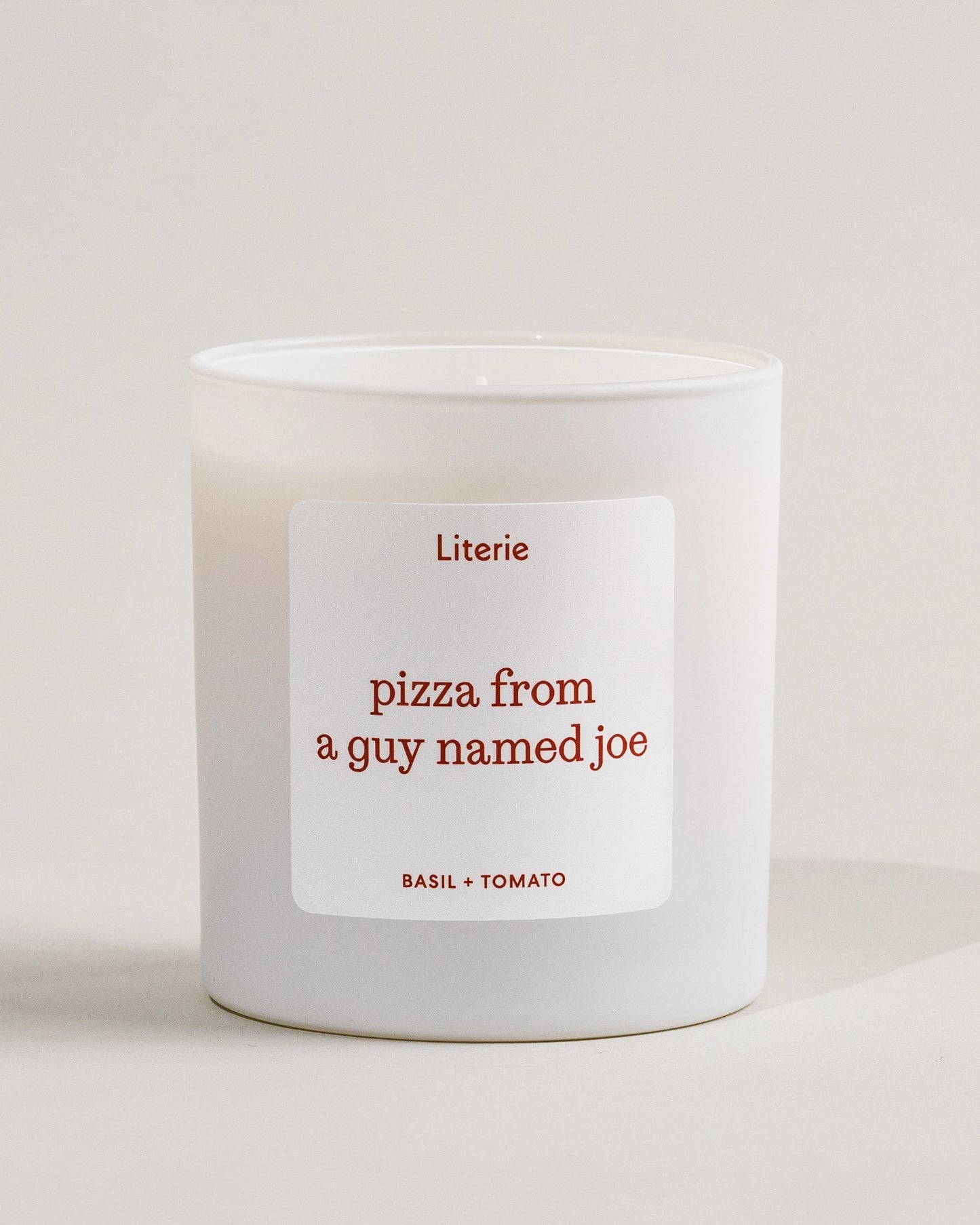 White Literie candle with a label reading 'pizza from a guy named Joe' on a light background