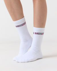 White Clueless socks with pink and black text on a light gray background