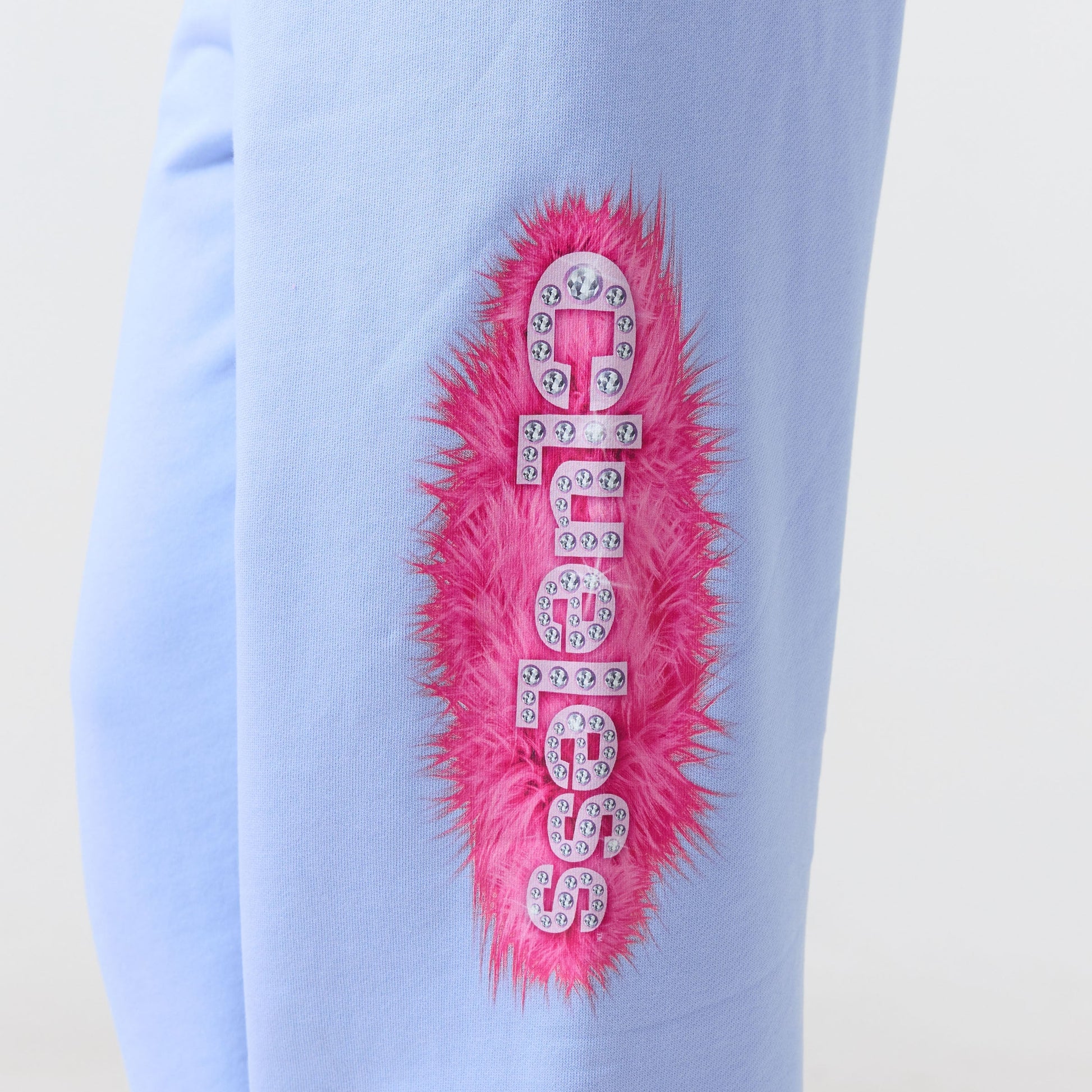 Light blue Clueless sweat pants with pink fur and rhinestone design on a plain background