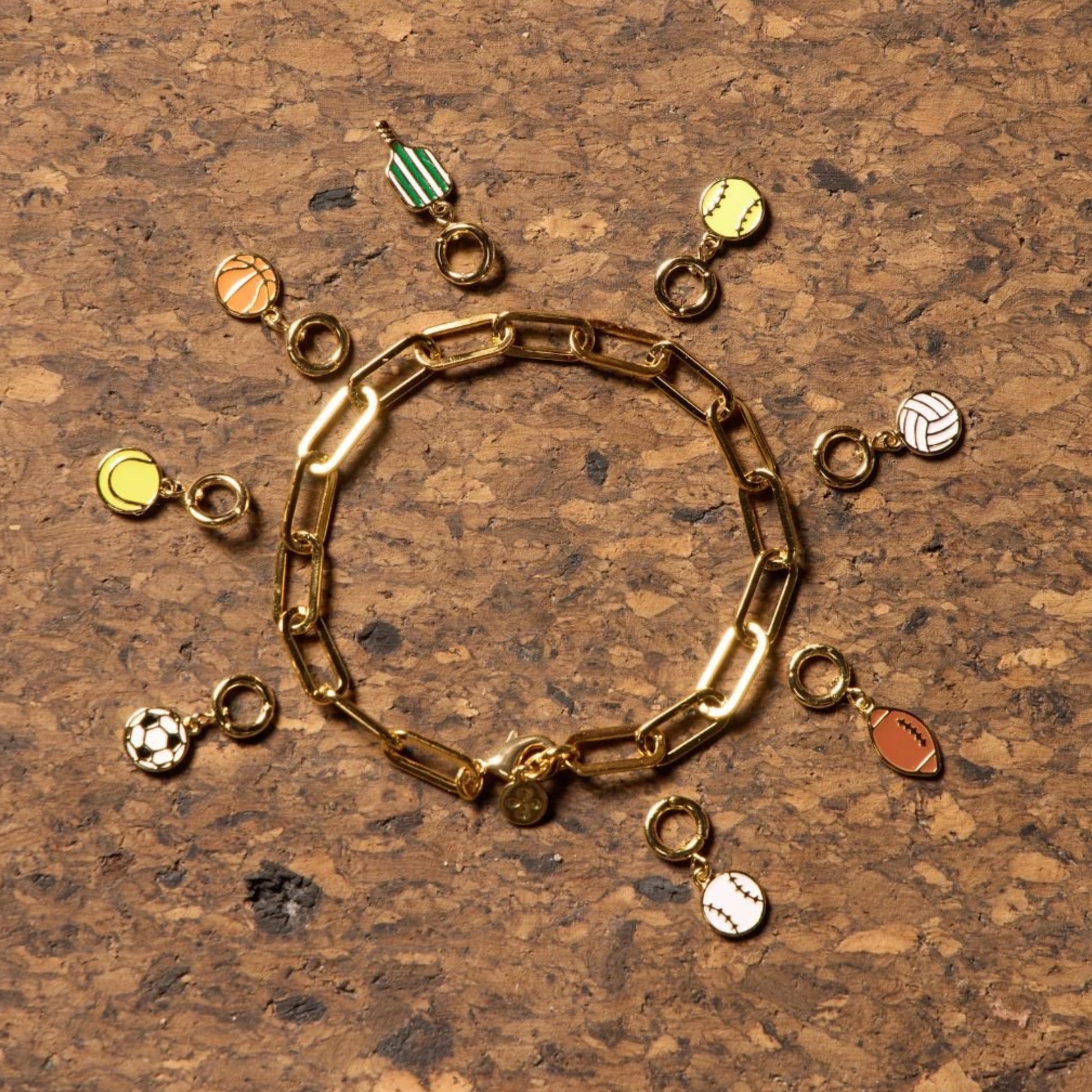Various sports jewelry charms on cork background.