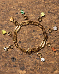 Various sports jewelry charms on cork background.