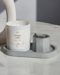 Grey concrete match stick holder with matches on a matching tray with a candle.