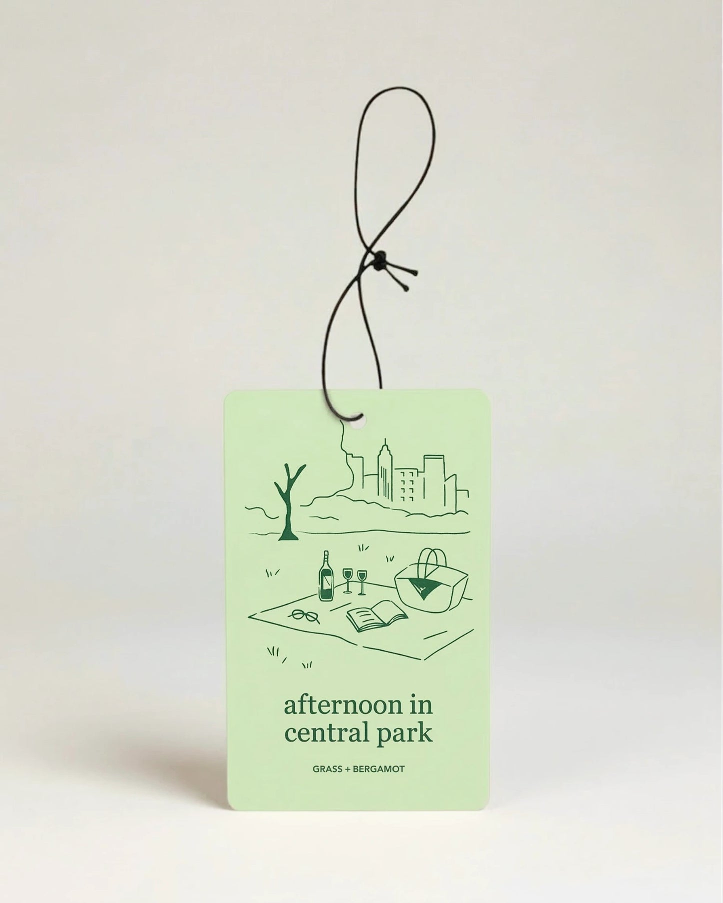 Light green air freshener with art illustration and text 'afternoon in central park' on a beige background