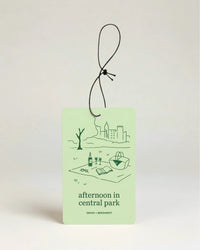 Light green air freshener with art illustration and text 'afternoon in central park' on a beige background