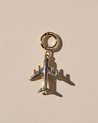 Gold airplane charm on a beige background