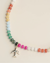 Necklace with colorful beads and airplane charm on a beige background