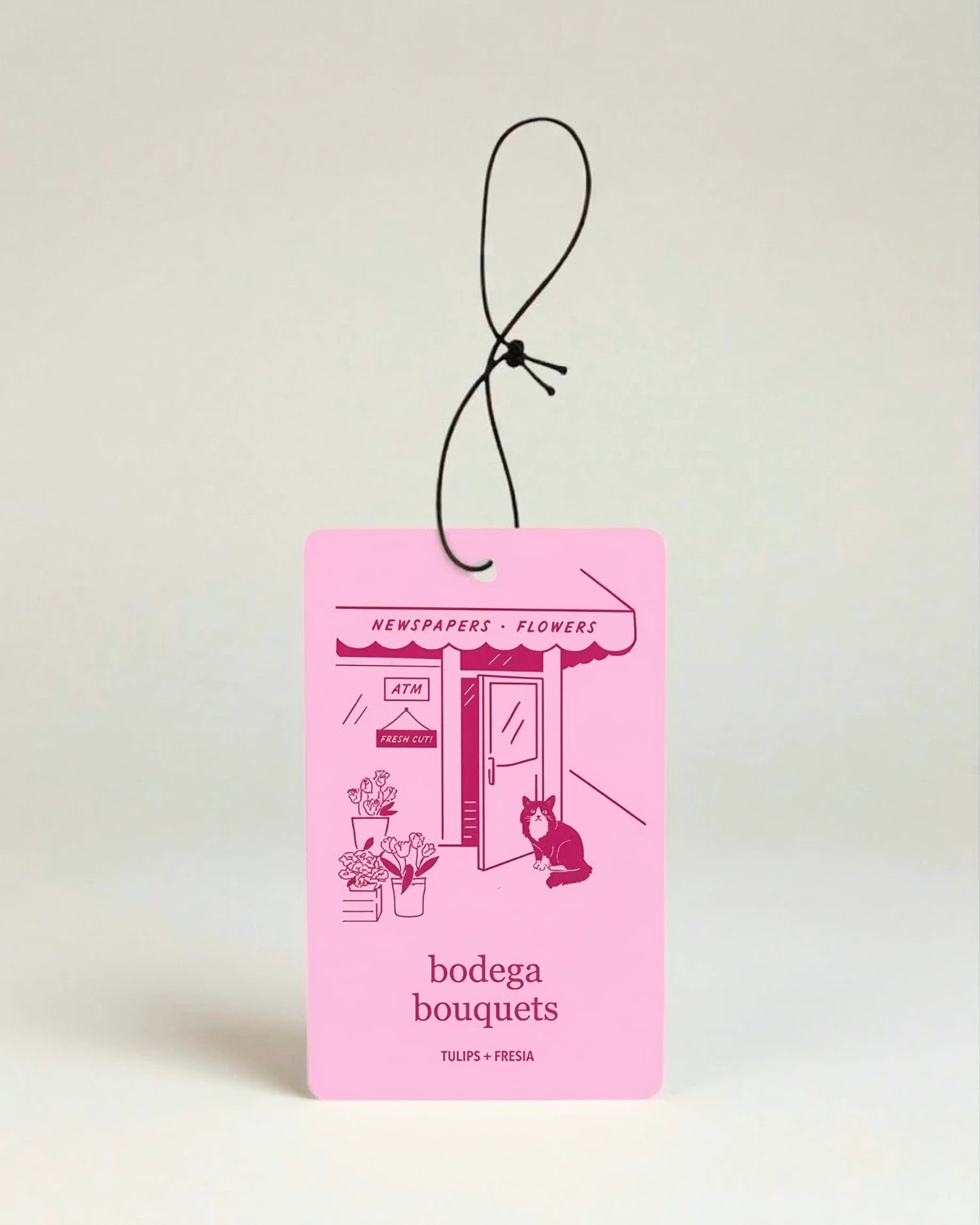Pink car air freshener with 'bodega bouquets' text and illustrations on a light beige background