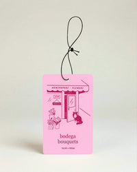 Pink car air freshener with 'bodega bouquets' text and illustrations on a light beige background