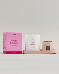 'bodega bouquets' candle and box siting on the pink candle tray next to the pink match holder with matches.