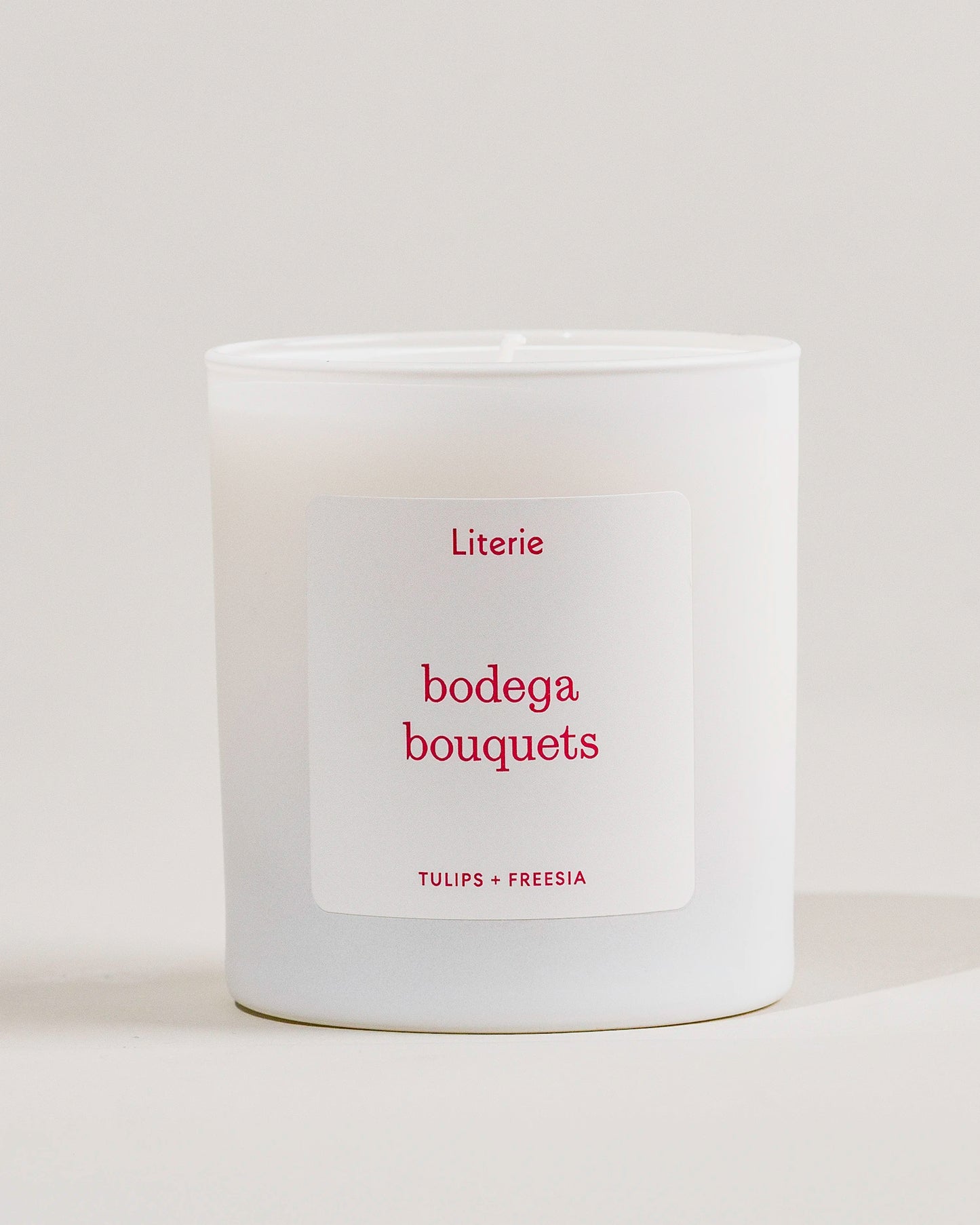 White Literie candle with a label saying 'bodega bouquets'  on a light gray background